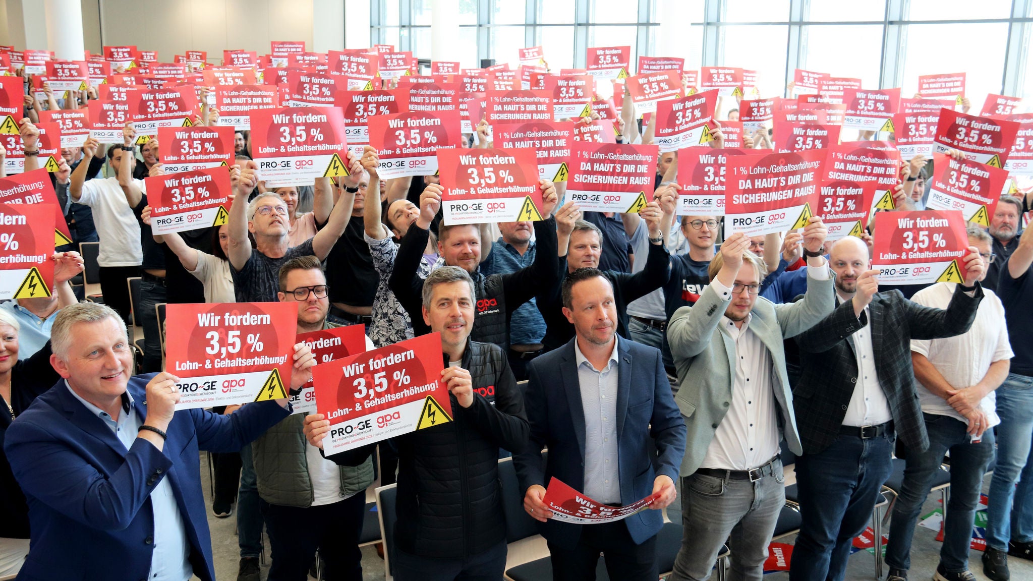 Teilnehmer:innen mit Schildern "Da haut's dir die Sicherungen raus" und "Wir fordern 3,5 Prozent"