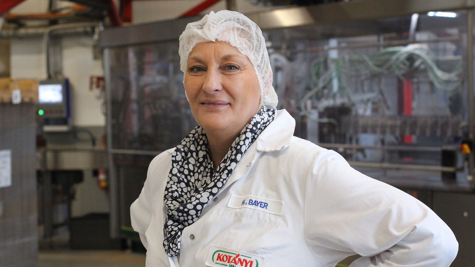 Betriebsrätin Helga Bayer in der Produktionshalle mit Arbeitsgewand.