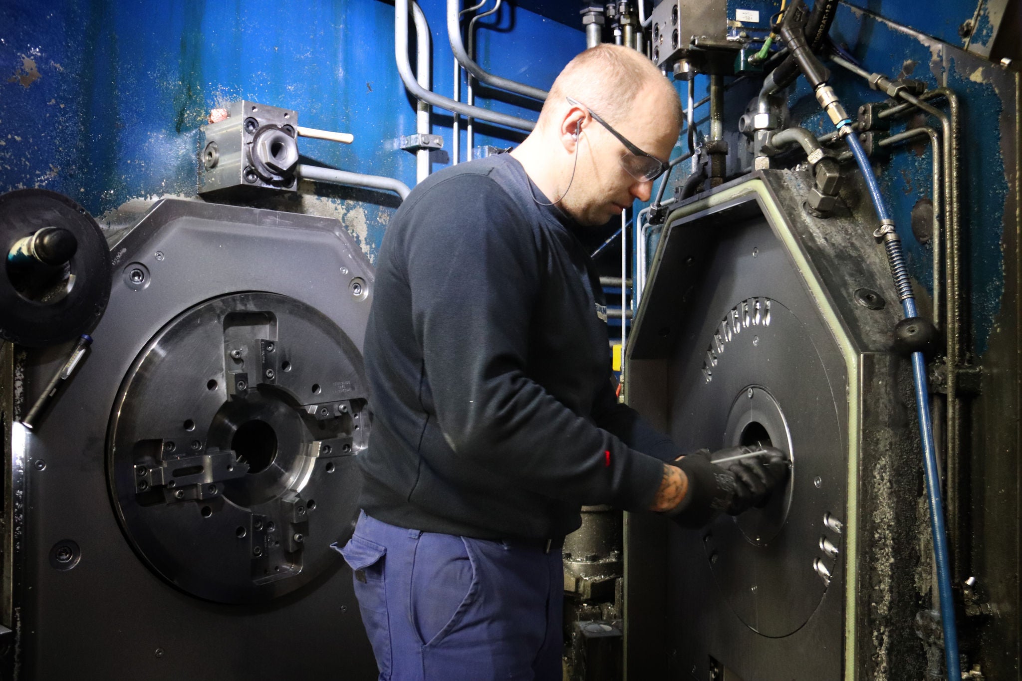Ein Arbeiter rüstet eine Stangenpressanlage gerade auf eine andere Größe um.
