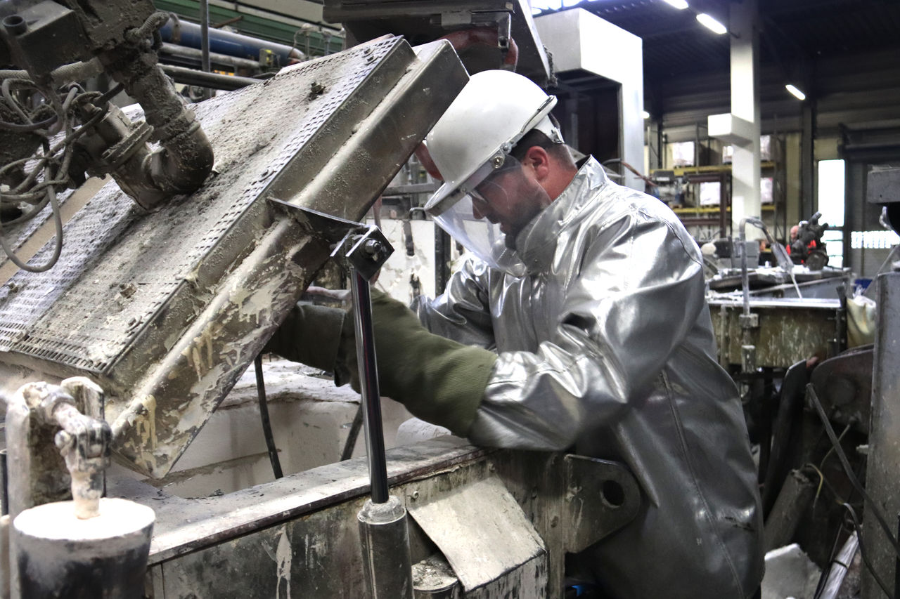 Ein Arbeiter reinigt mit Hitzeschutz-Anzug gerade Keramikfilter.
